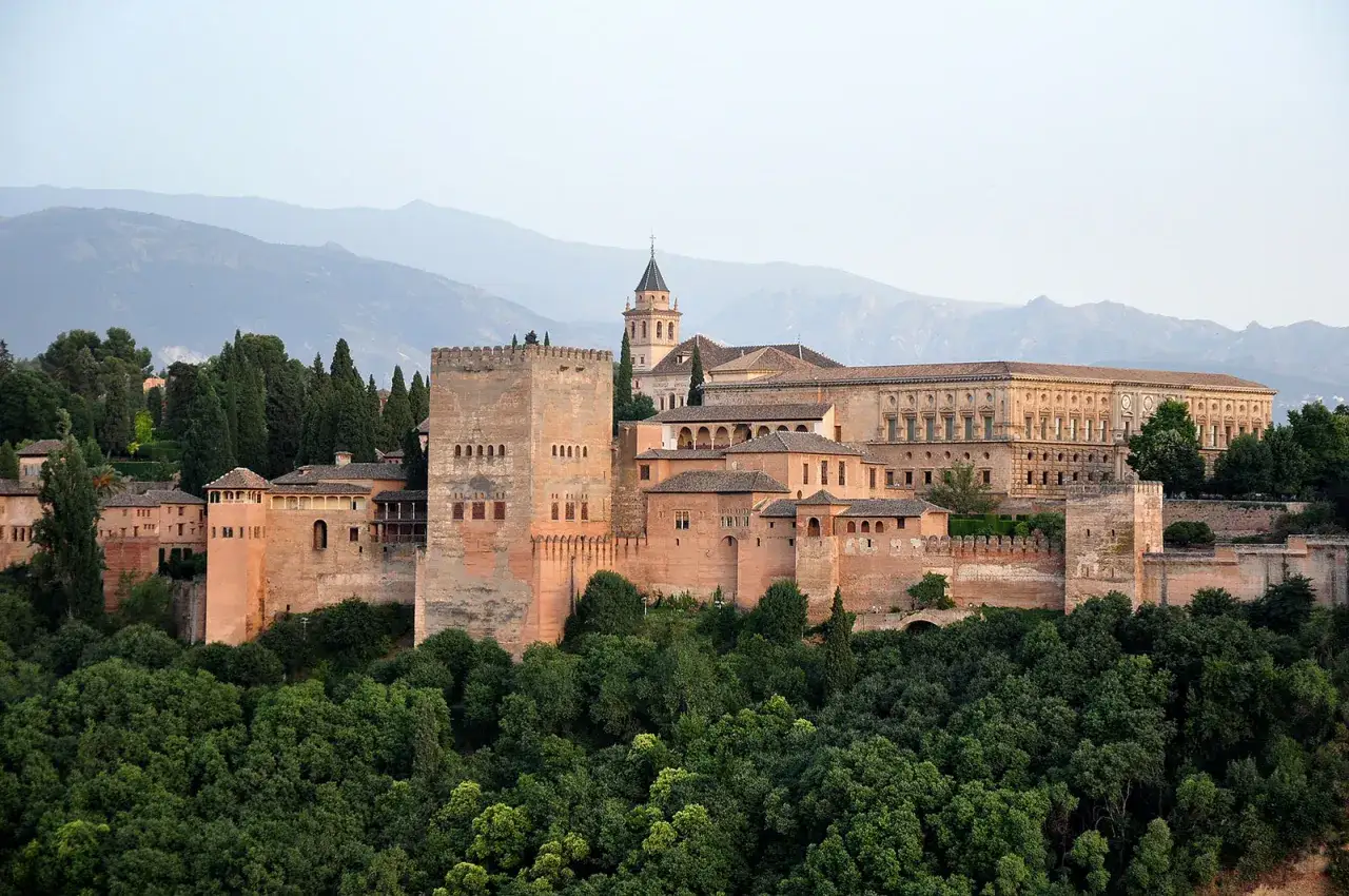 Majestatyczna Alhambra w Hiszpanii, wznosząca się nad zielonymi wzgórzami, zachwyca swoją architekturą.