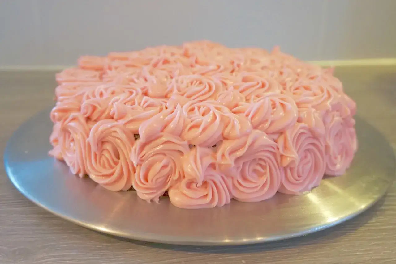 En vacker glutenfri morotskaka dekorerad med rosa frosting som rosor.