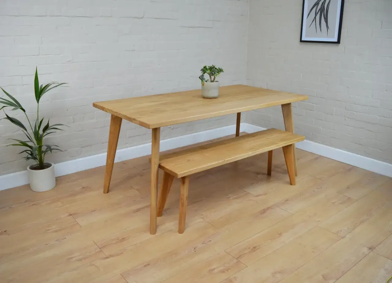 Minimalist oak dining set with bench, perfect for modern dining room ideas. A potted plant adds a touch of green.