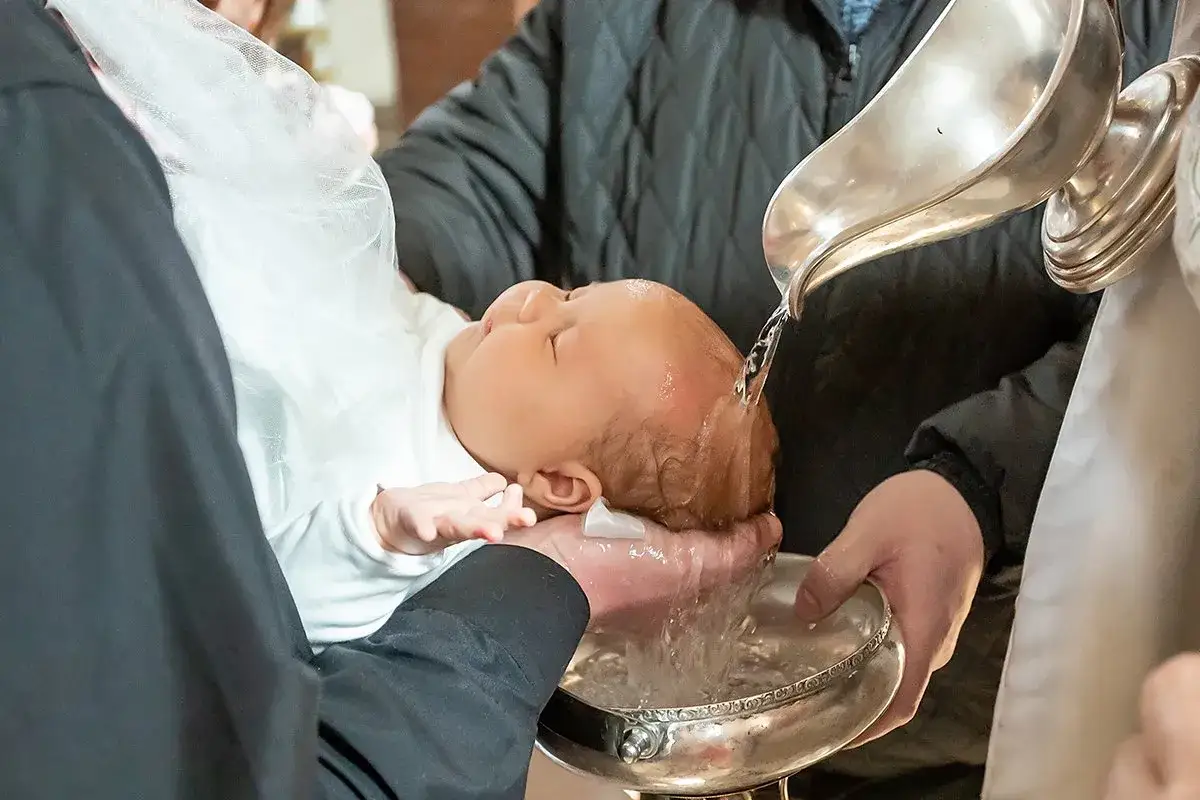 A baby is baptized as water is poured over their head. This sacred ritual shows how to baptize someone in a moment of spiritual cleansing.