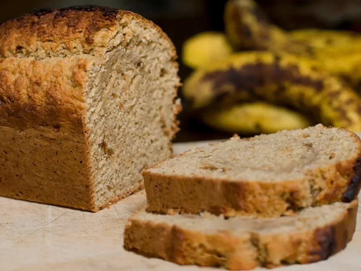 Ein frisch gebackener Kuchen mit Bananen, daneben liegen reife Bananen.