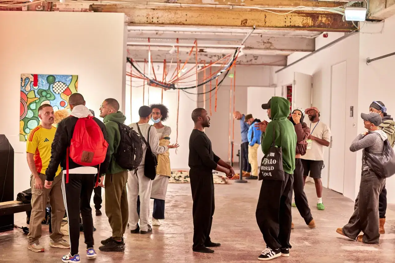 People gather at an art exhibition, discussing the vibrant abstract painting, a scene typical of the best galleries for emerging artists.