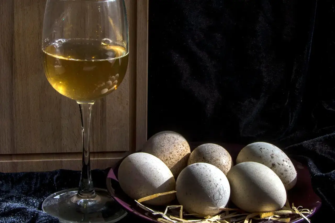 Un calice di vino dorato e un piatto di uova maculate, un'idea su cosa abbinare alle uova per un pasto rustico.