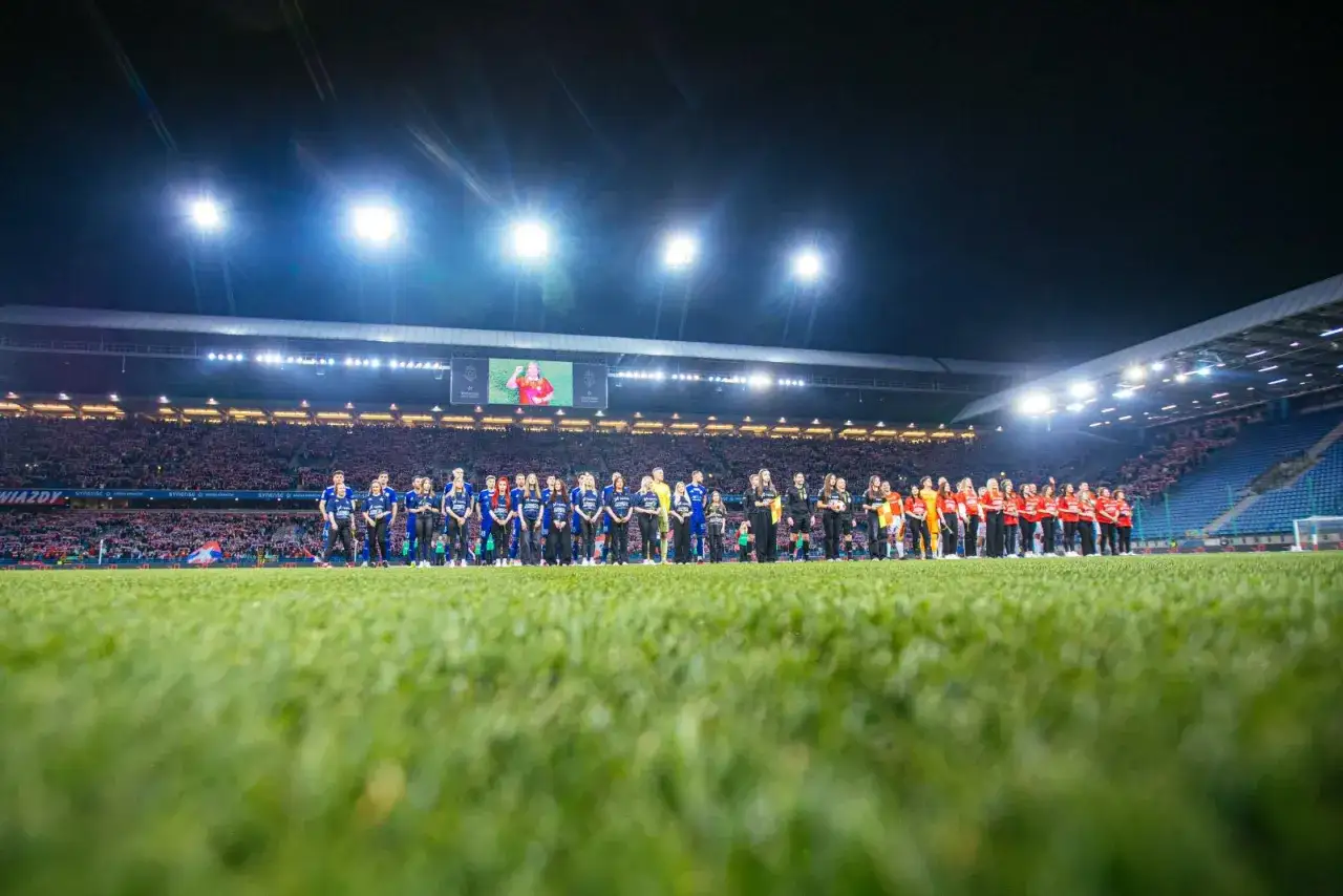 Piłkarze Wisły Kraków i Miedzi Legnica stoją na murawie stadionu przed meczem.
