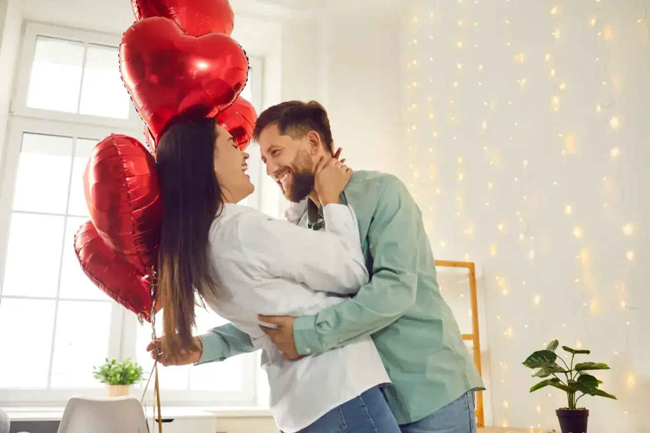 Para świętuje miłość, trzymając bukiet czerwonych balonów w kształcie serca. Ich uśmiechy i objęcia mówią o głębokim uczuciu, jakby ich serca biły w tej samej wadze.