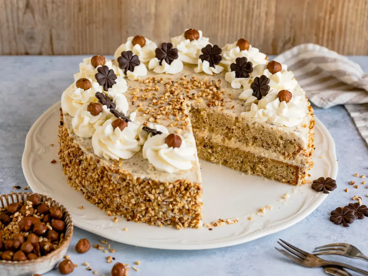 Eine köstliche nusstorte mit buttercreme, verziert mit Haselnüssen und Schokoladenkleeblättern.