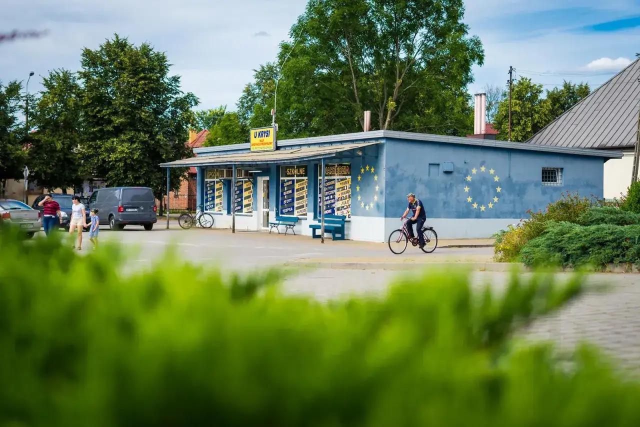 Mężczyzna na rowerze przejeżdża obok sklepu
