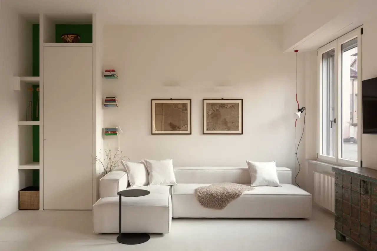 Soggiorno accogliente in mini appartamenti, con divano bianco, quadri antichi e arredi moderni.
