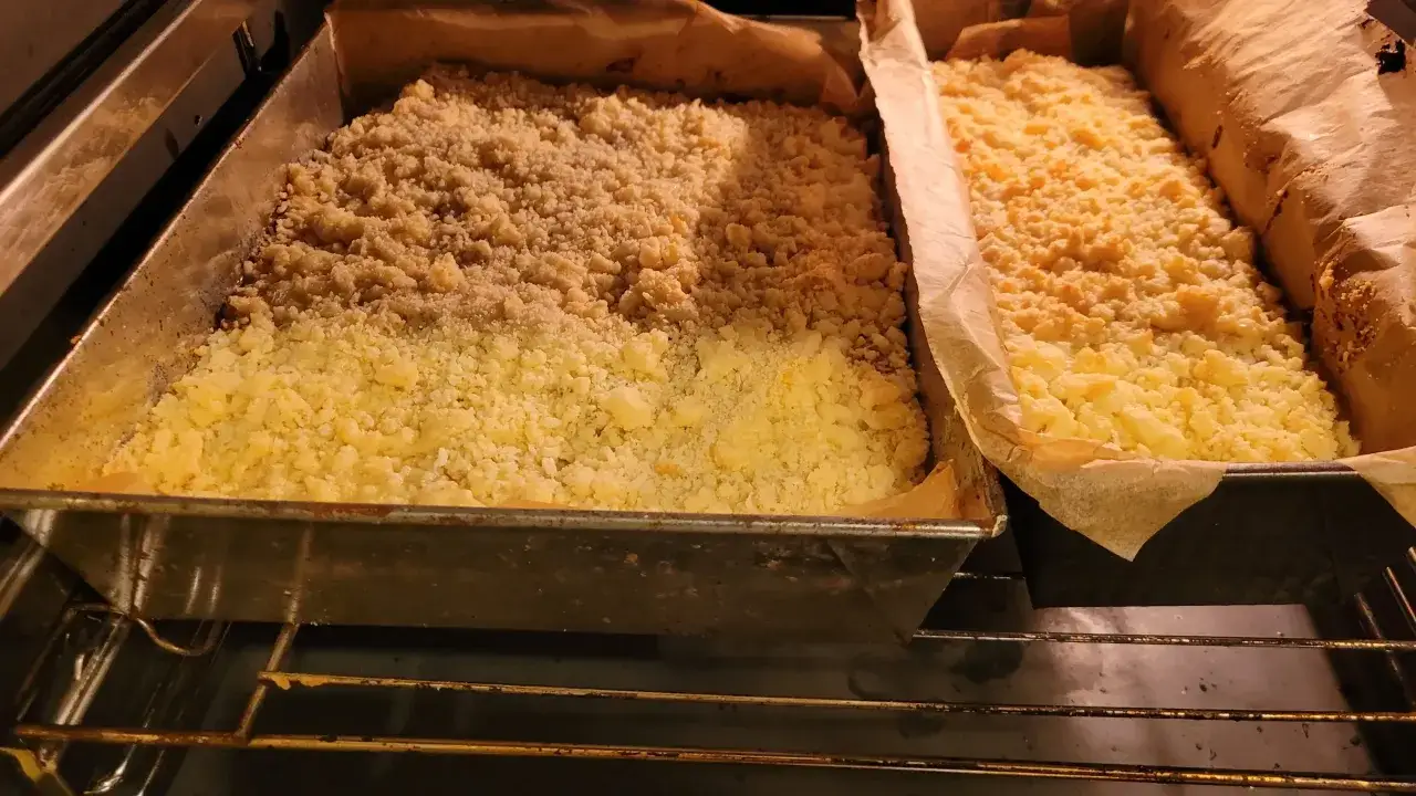 Dwa ciasta z kruszonką pieką się w piekarniku, na środkowym poziomie.