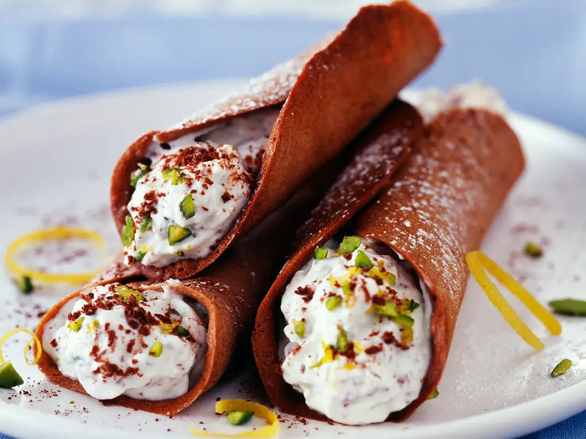 Trois cannoli sal&eacute;s au chocolat, garnis d'une cr&egrave;me onctueuse, de pistaches concass&eacute;es et de zestes de citron.