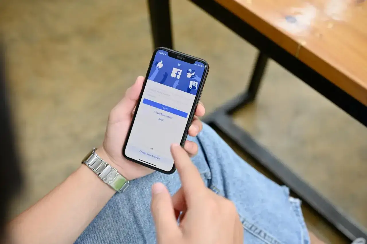 Person håller upp en mobil med Facebook-inloggningssida. Kanske blev lurad på Marketplace.
