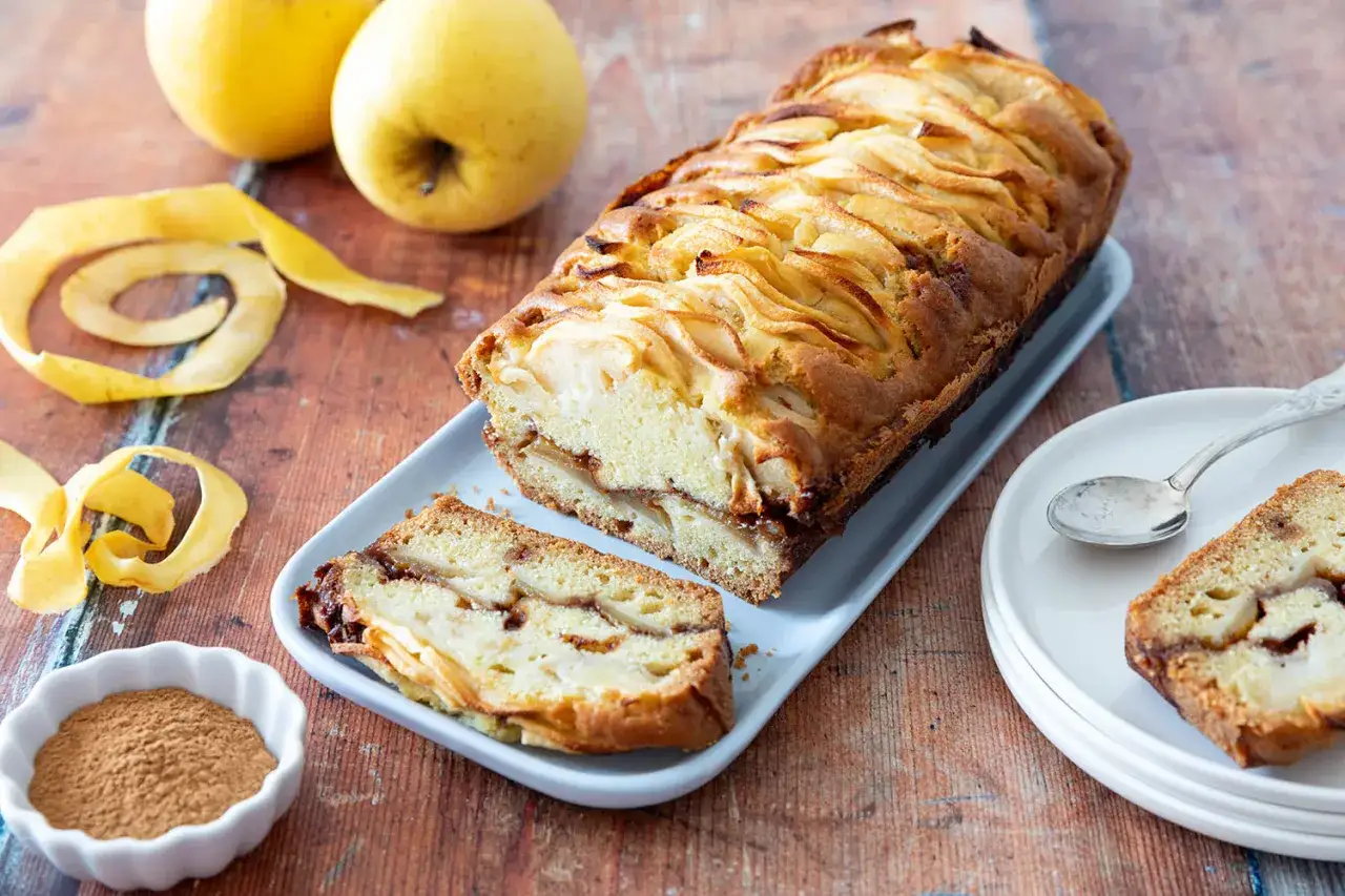 Gâteau rustique aux pommes, garni de tranches de pommes et servi avec une tranche coupée.