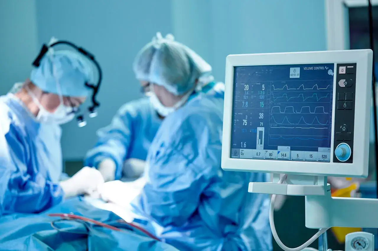 Chirurdzy podczas operacji, monitor parametrów życiowych. Obraz symbolizuje dylematy etyczne związane z transplantacją organów a religia.