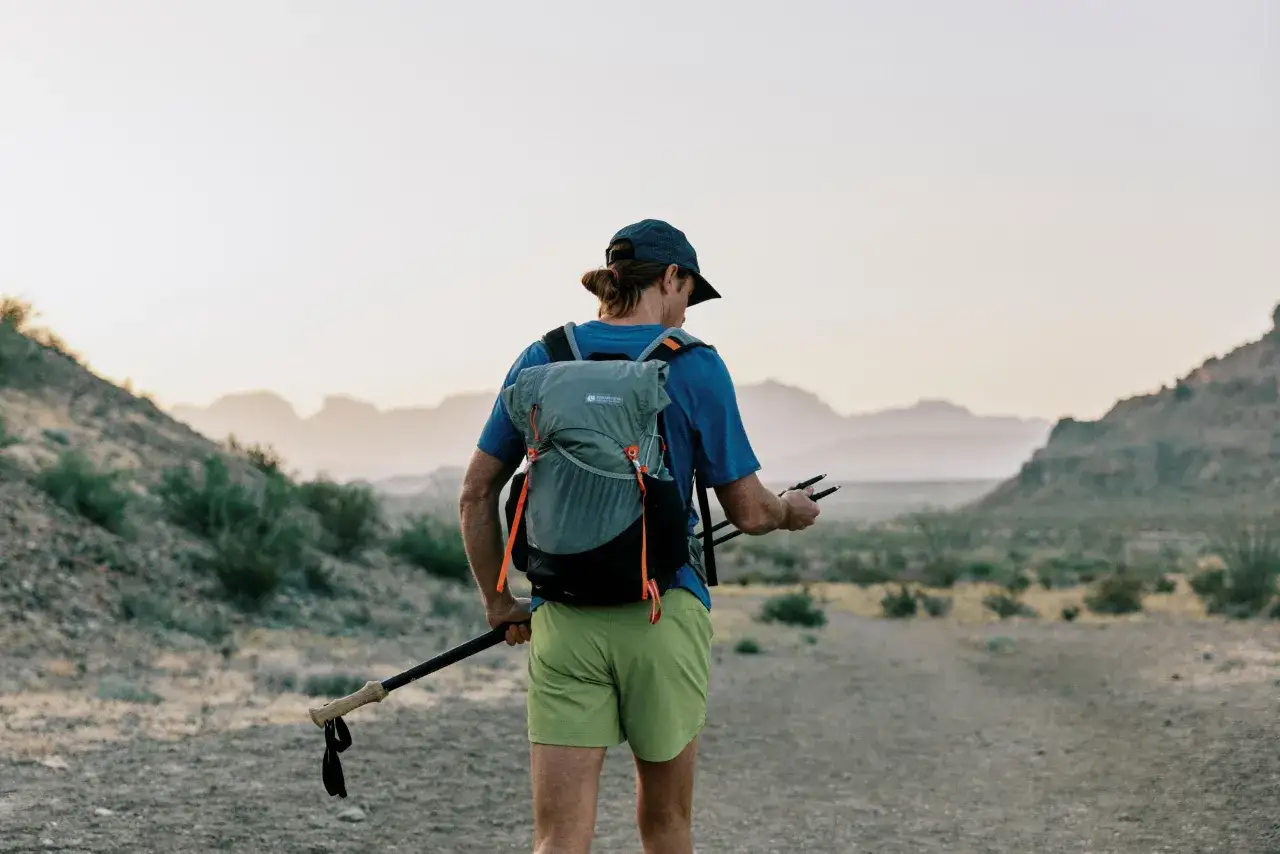 Randonneur avec sac &agrave; dos et b&acirc;tons de marche, pr&ecirc;t &agrave; explorer un paysage d&eacute;sertique. Un guide pour comment choisir des b&acirc;tons de marche.