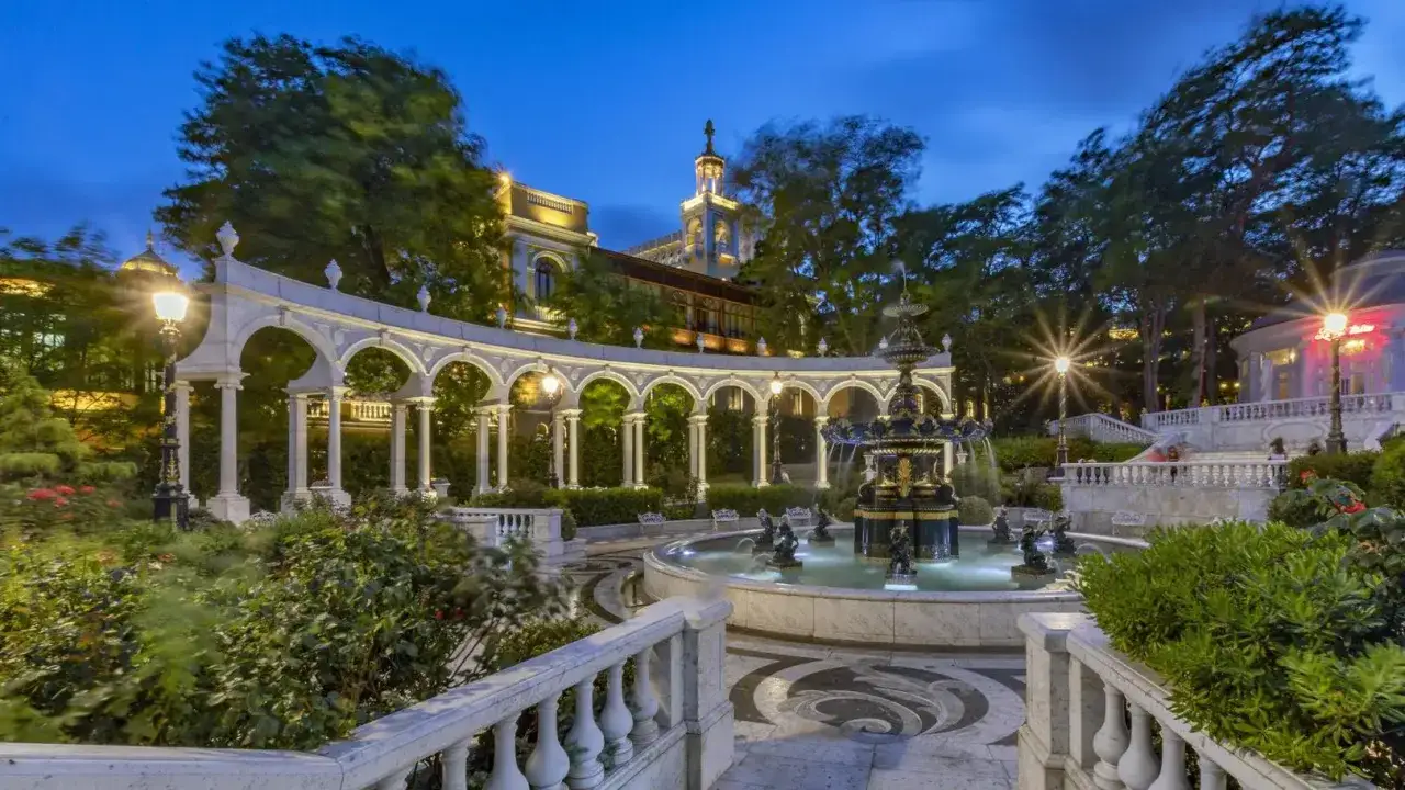 Urokliwy park w Baku, **Azerbejdżan**, z fontanną i arkadami oświetlonymi nocą.