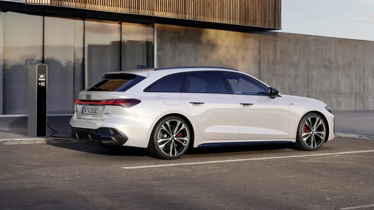 Vit Audi A5 hybrid laddas vid en laddstation. Modern design m&ouml;ter h&aring;llbarhet.