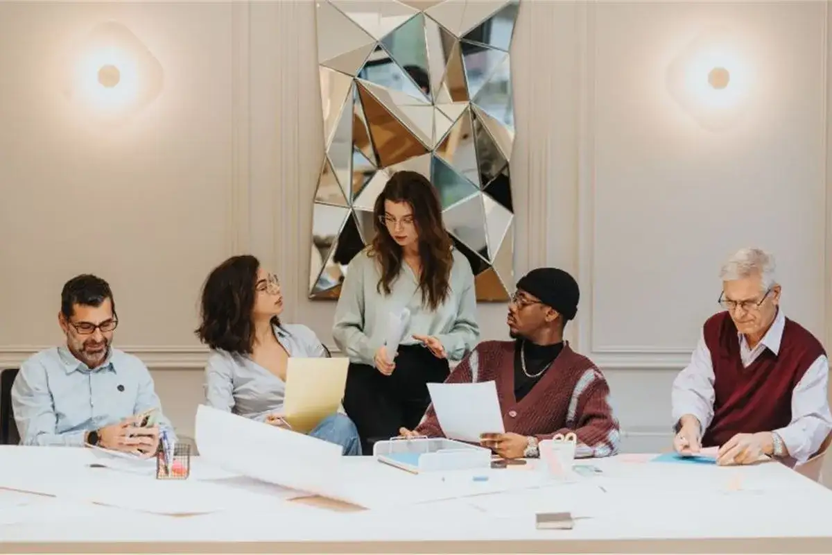 A diverse group discusses ideas, showcasing cultural differences between generations in a modern office setting.