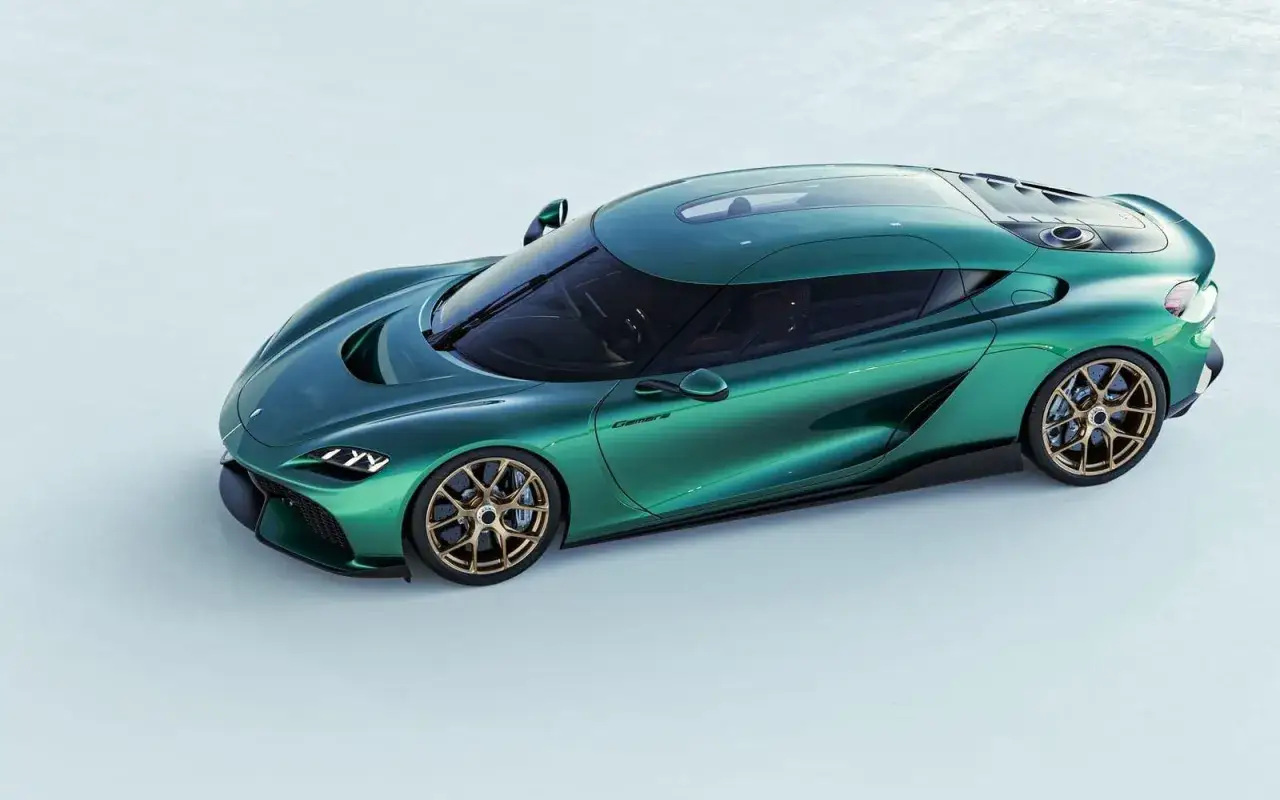 En smaragdgrön Koenigsegg bil med guldfärgade fälgar står på en ljus bakgrund.