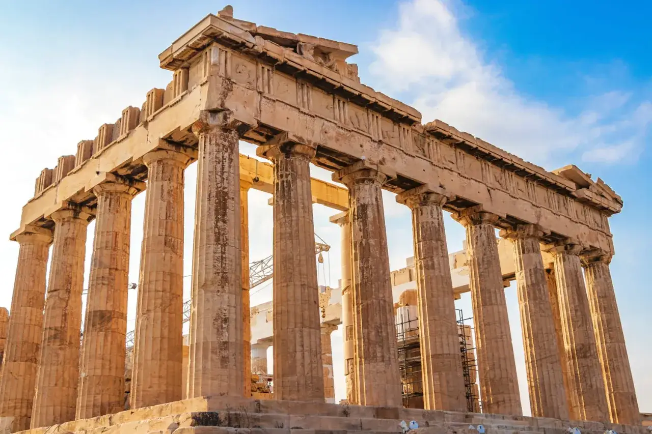 Le Parthénon d'Athènes, majestueux temple antique, se dresse sous un ciel bleu. Ses colonnes doriques imposantes témoignent de la grandeur de la civilisation grecque.