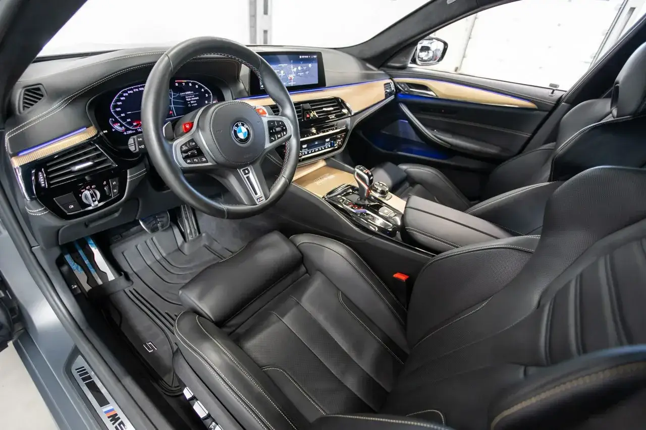 Wnętrze BMW M5 F90 z czarną skórzaną tapicerką, sportową kierownicą i nowoczesnym panelem.