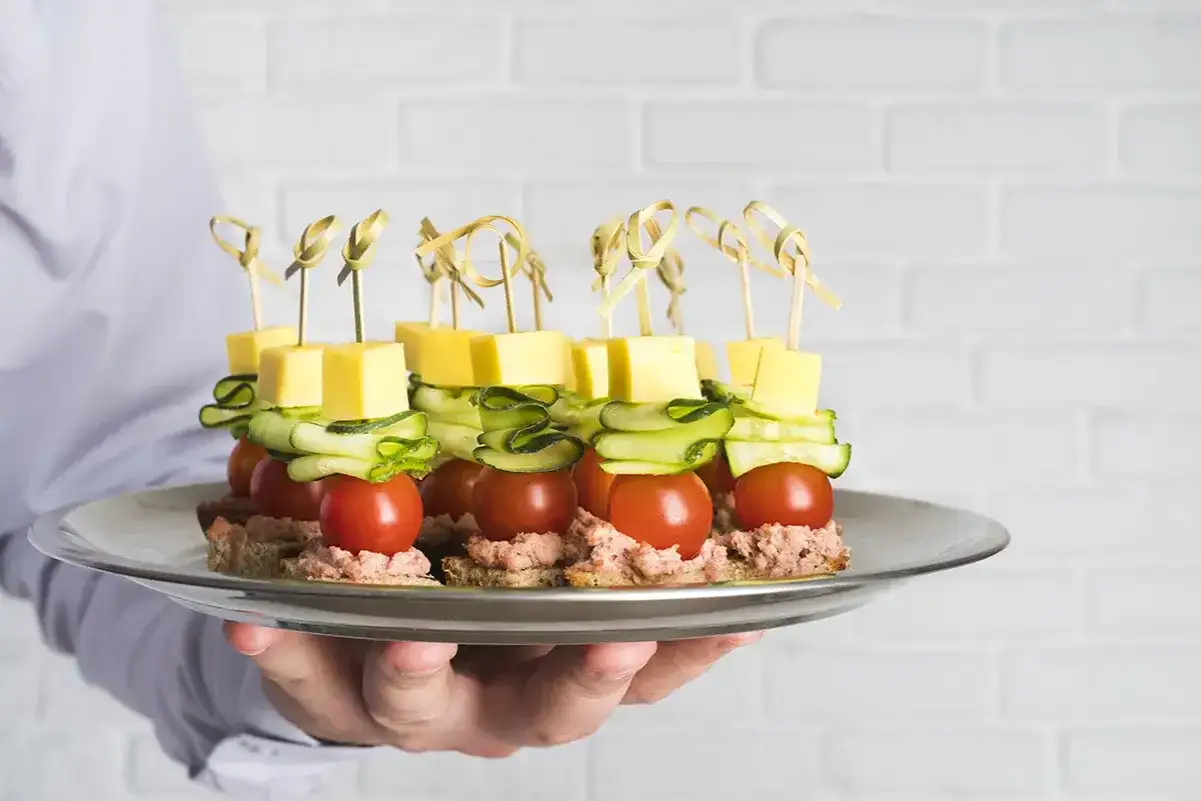 Plate of mini brochettes apéritives sans cuisson : tomates cerises, concombre, fromage et tartinade sur pain.