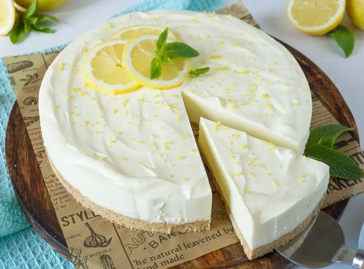 Cremige Philadelphia Torte mit Zitronenscheiben und Minze, ein Stück wurde bereits angeschnitten.
