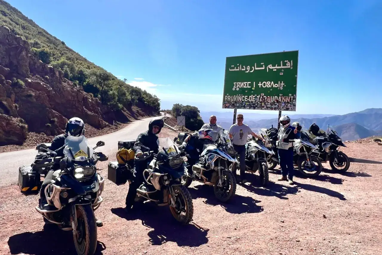 Amici in moto esplorano i **Marocco in moto itinerari** con un cartello 