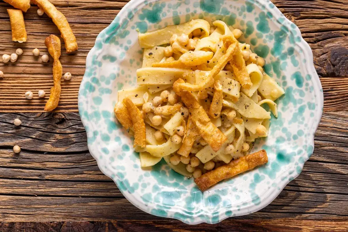 Ciceri e tria otranto: pasta fresca con ceci e sfoglie croccanti, un piatto tradizionale pugliese servito in un piatto decorato.