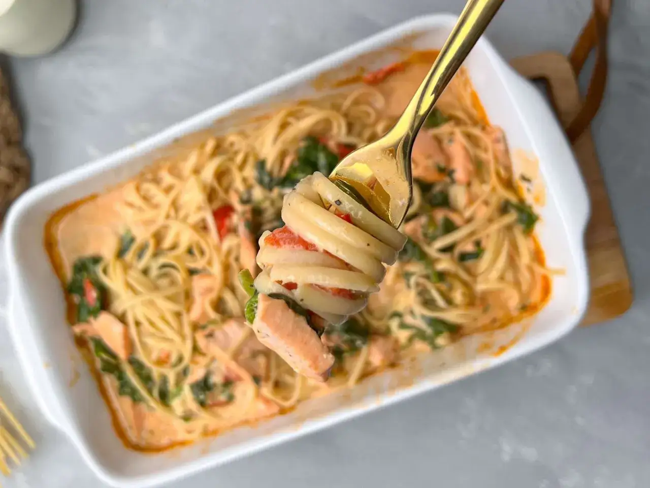 Cremige Pasta mit Lachs und Spinat, auf einer goldenen Gabel serviert. Ein k&ouml;stliches Gericht, das Lust auf mehr macht.