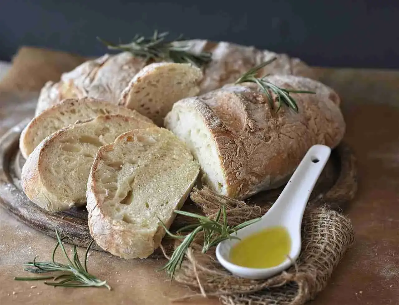 Frisches Brot, ein Symbol für italienische Brotsorten, wird mit Rosmarin und Olivenöl serviert.