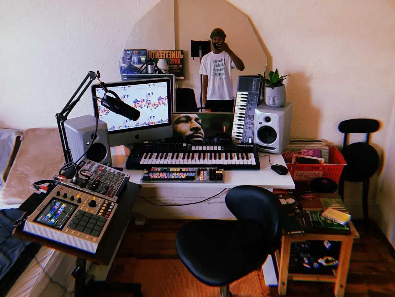 Un studio de musique lo fi avec un homme se reflétant dans un miroir, des claviers, un microphone et des platines.