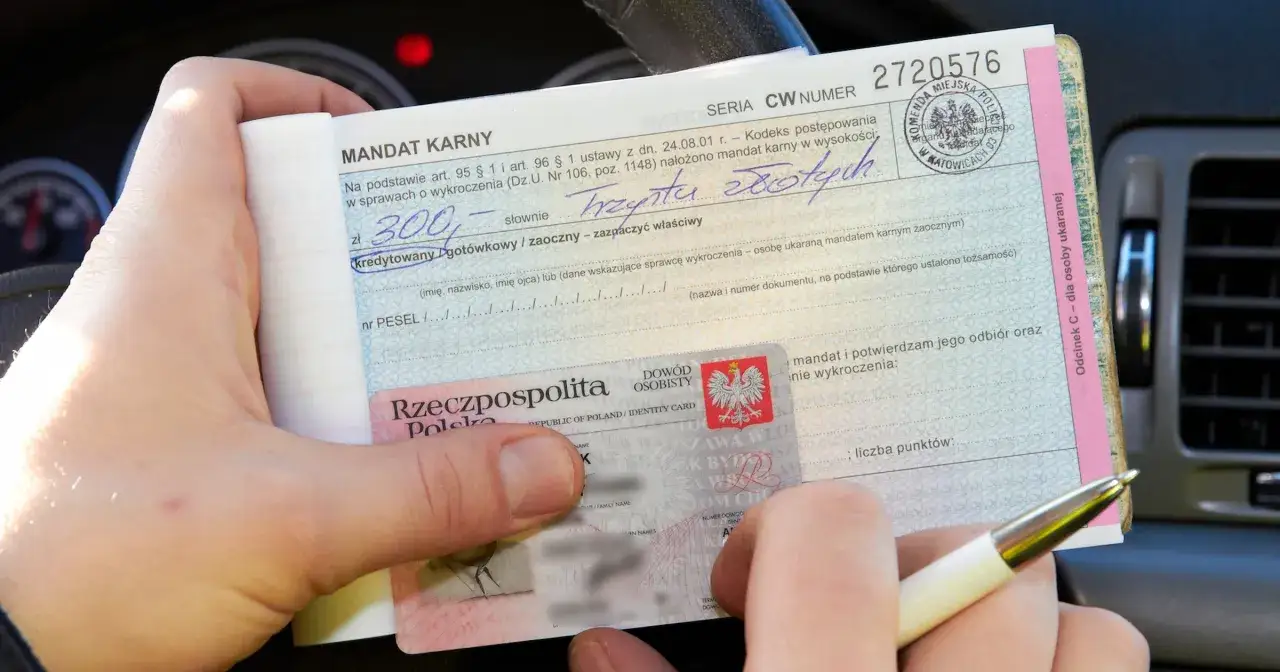 Ręka trzyma mandat karny na kwotę 300 zł, obok dowód osobisty. To nieprzyjemna grzywna, ale mandat jest ważny.