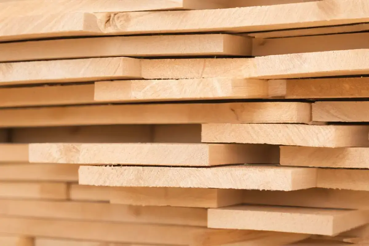 Impilamento di tavole di legno chiaro, un esempio di cos'&egrave; il legno compensato, con venature visibili e bordi squadrati.