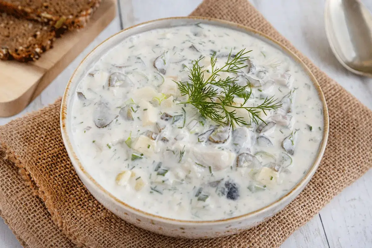 Schmackhafter Heringssalat Hausfrauenart in einer Schüssel, garniert mit Dill. Dazu gibt es dunkles Brot.