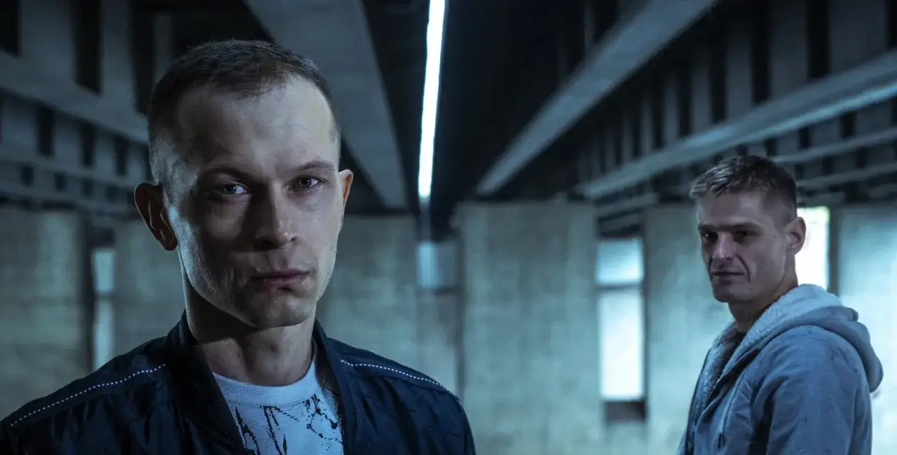 Dwaj mężczyźni w mrocznym wnętrzu, ujęcie z filmu