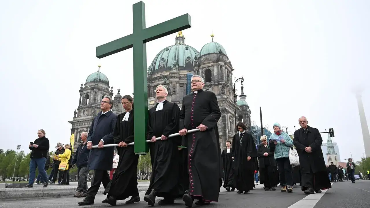 Geistliche tragen ein großes grünes Kreuz vor dem Berliner Dom. Ein Gedenken, was war am Karfreitag.