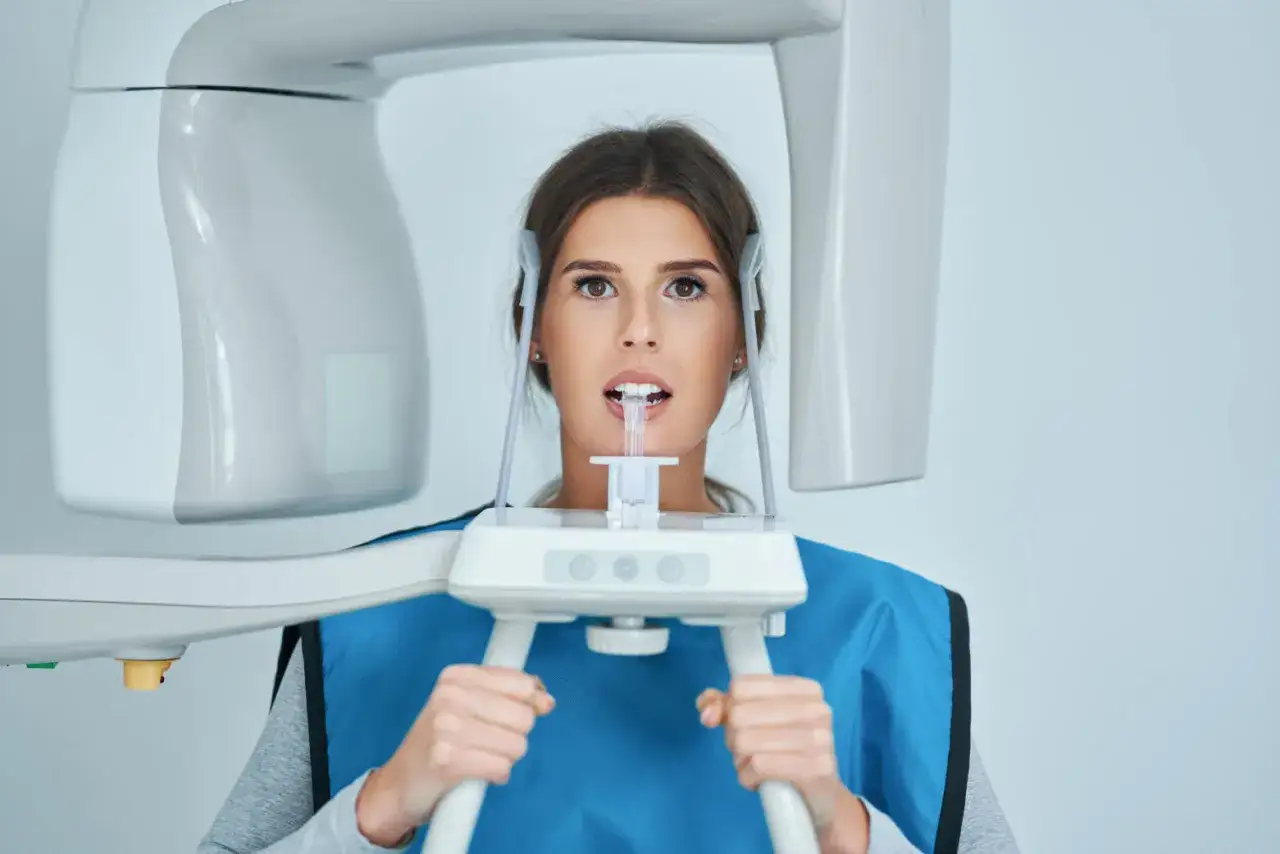 Kobieta poddaje się badaniu CBCT w gabinecie stomatologicznym.