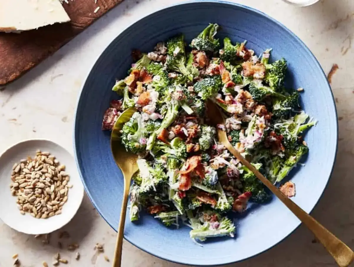 Ein k&ouml;stlicher low carb salat mit Brokkoli, Speck und Sonnenblumenkernen in einer blauen Sch&uuml;ssel, bereit zum Servieren.