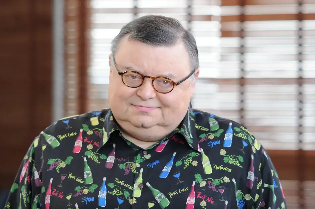 Wojciech Mann, znany z poczucia humoru, w koszuli z motywem win. Jego wiek nie przeszkadza mu w cieszeniu się życiem.