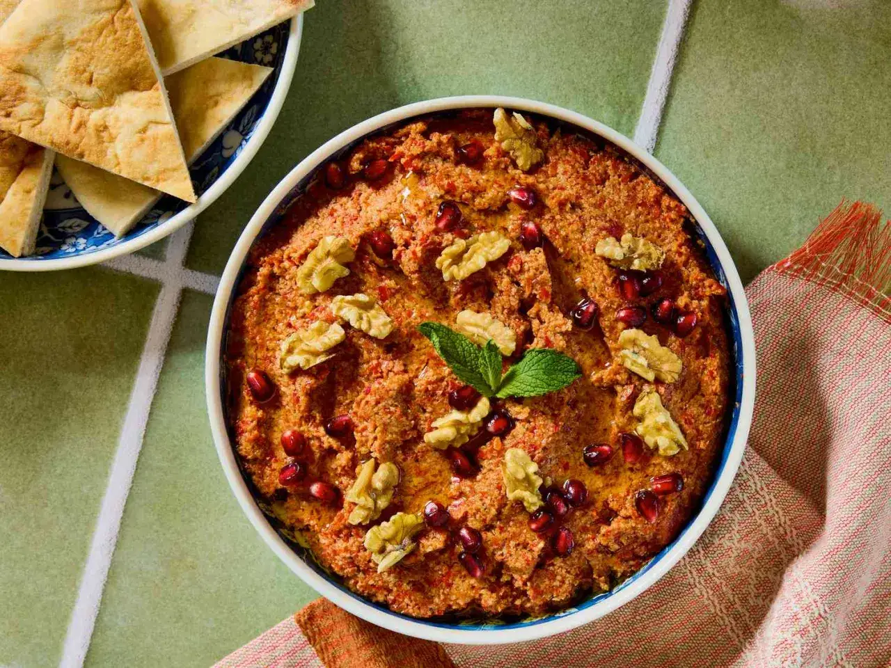 En sk&aring;l med muhammara, toppad med valn&ouml;tter, granat&auml;ppelk&auml;rnor och mynta. Serveras med pitabr&ouml;d.