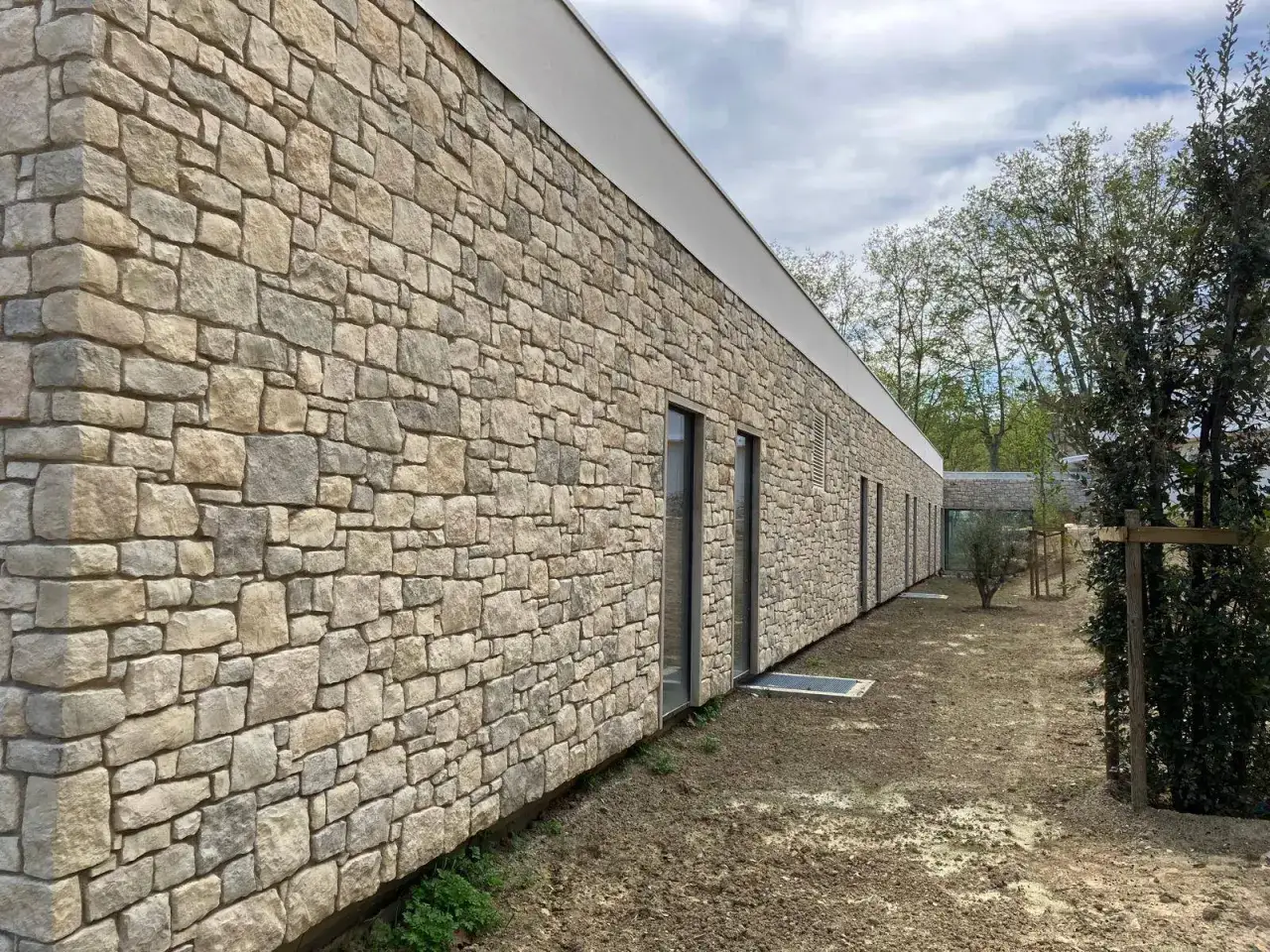 Façade d'une maison en pierre naturelle, offrant une isolation robuste et un charme intemporel. Le revêtement mural en pierres irrégulières crée une texture visuelle unique.