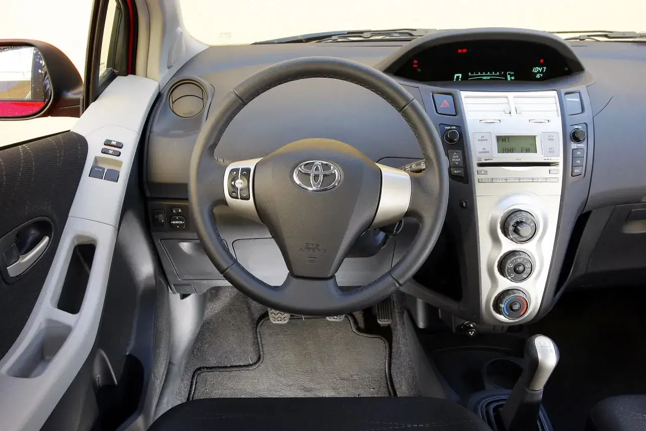 Wnętrze Toyoty Yaris 2008: kierownica, radio, panel klimatyzacji i dźwignia zmiany biegów.
