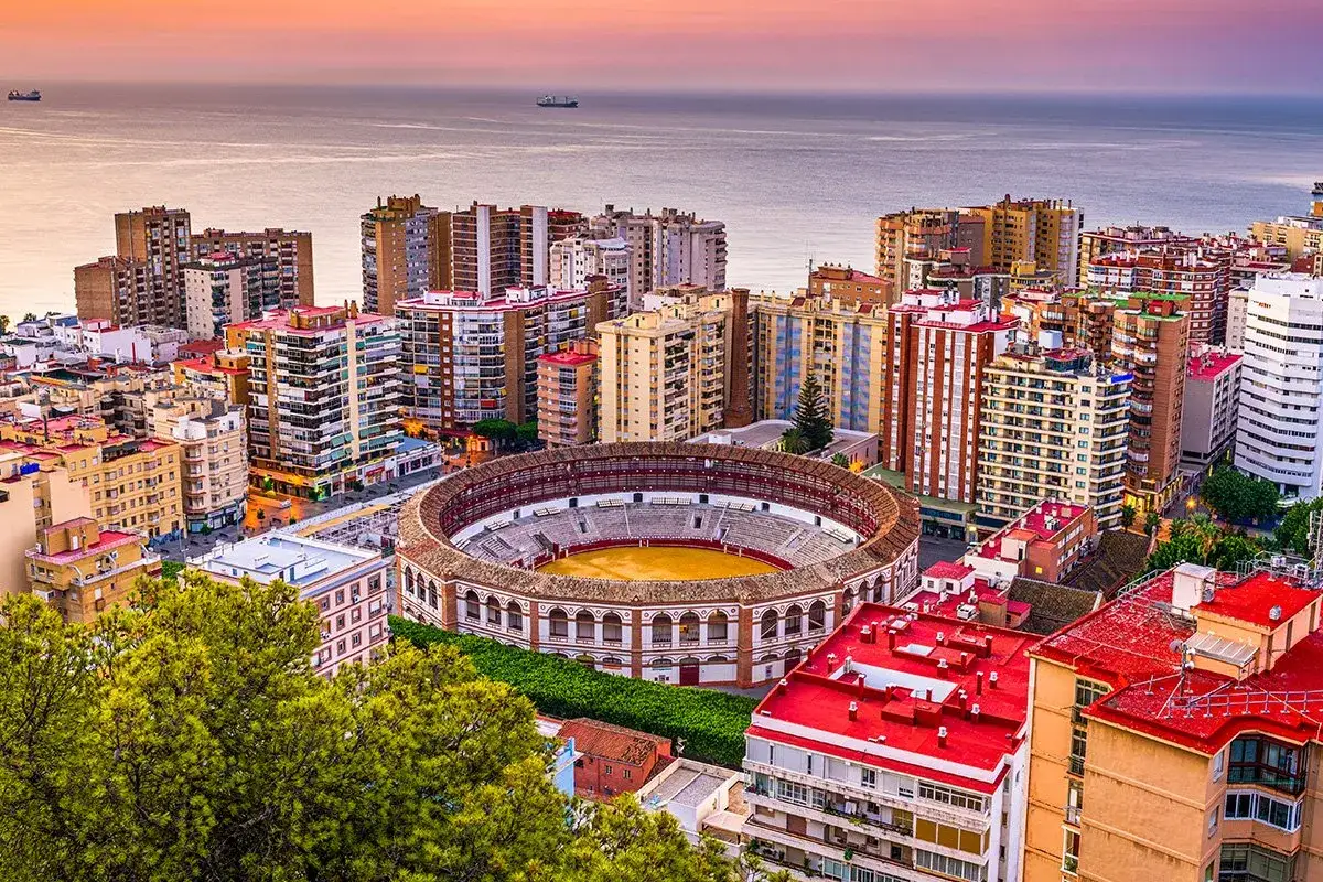 Malaga co zobaczyć? Arena La Malagueta i nadmorska panorama miasta o zachodzie słońca.