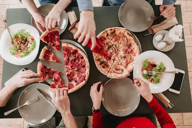 ludzie jedzący pizzę w pizzerii