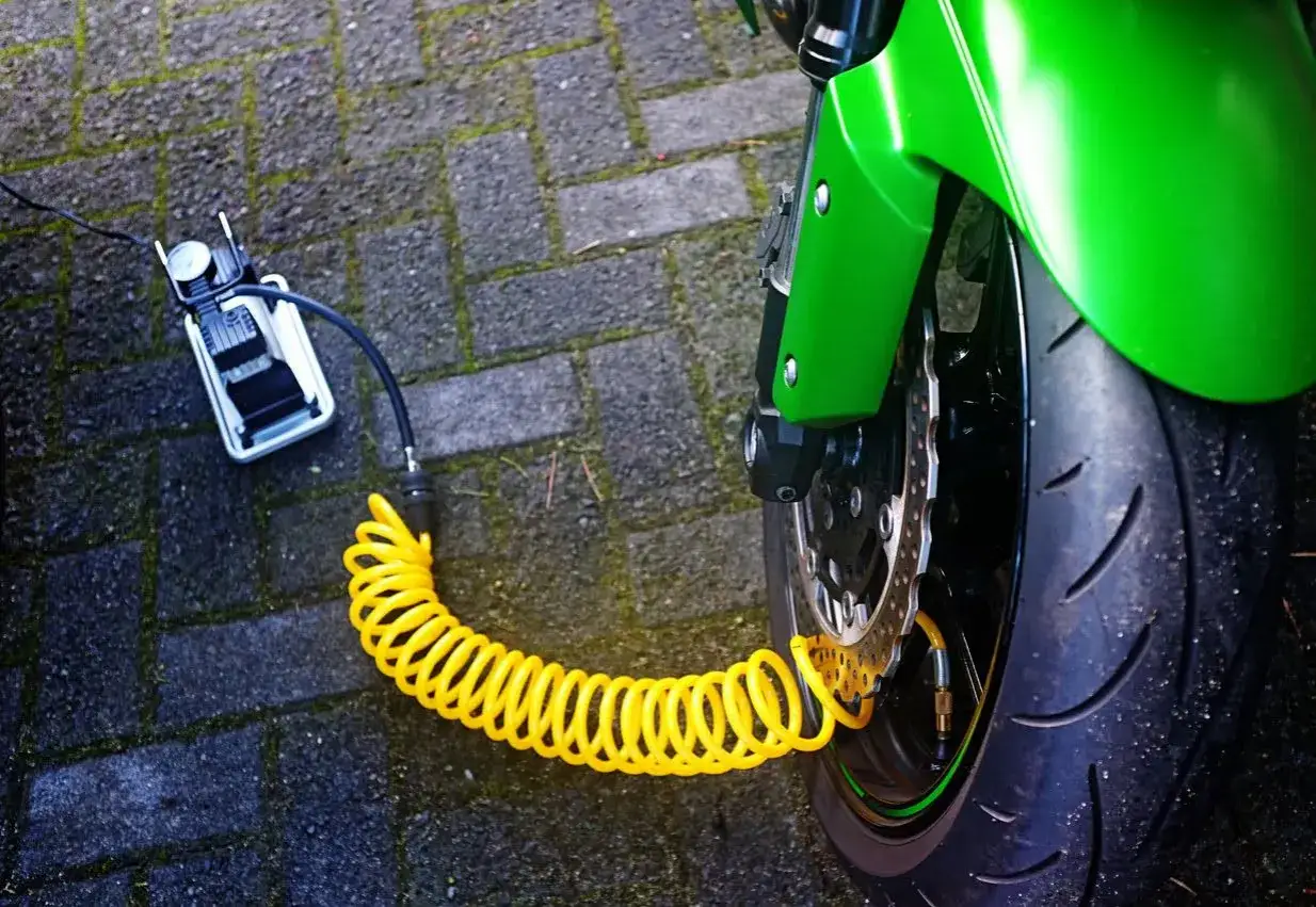 Un compresor portátil conectado a un neumático de moto para hincharlo con nitrógeno.