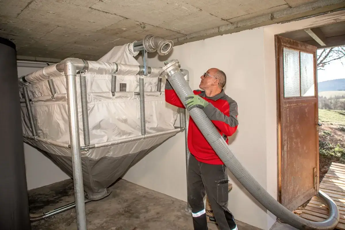 Mann schlie&szlig;t Schlauch an Pellet-Silo an. So kann man Pellets lagern, ohne dass sie Feuchtigkeit ziehen.