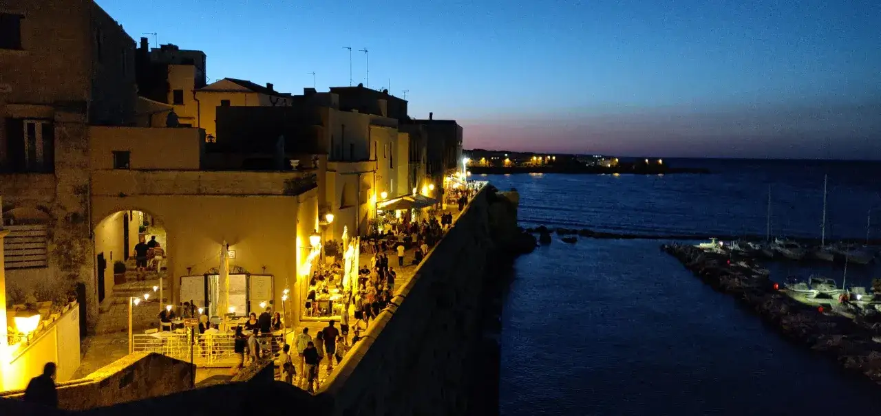 Serata a Otranto: passeggiata sul lungomare illuminato, ristoranti affollati e barche nel porto. Ecco cosa vedere a Otranto in un giorno.