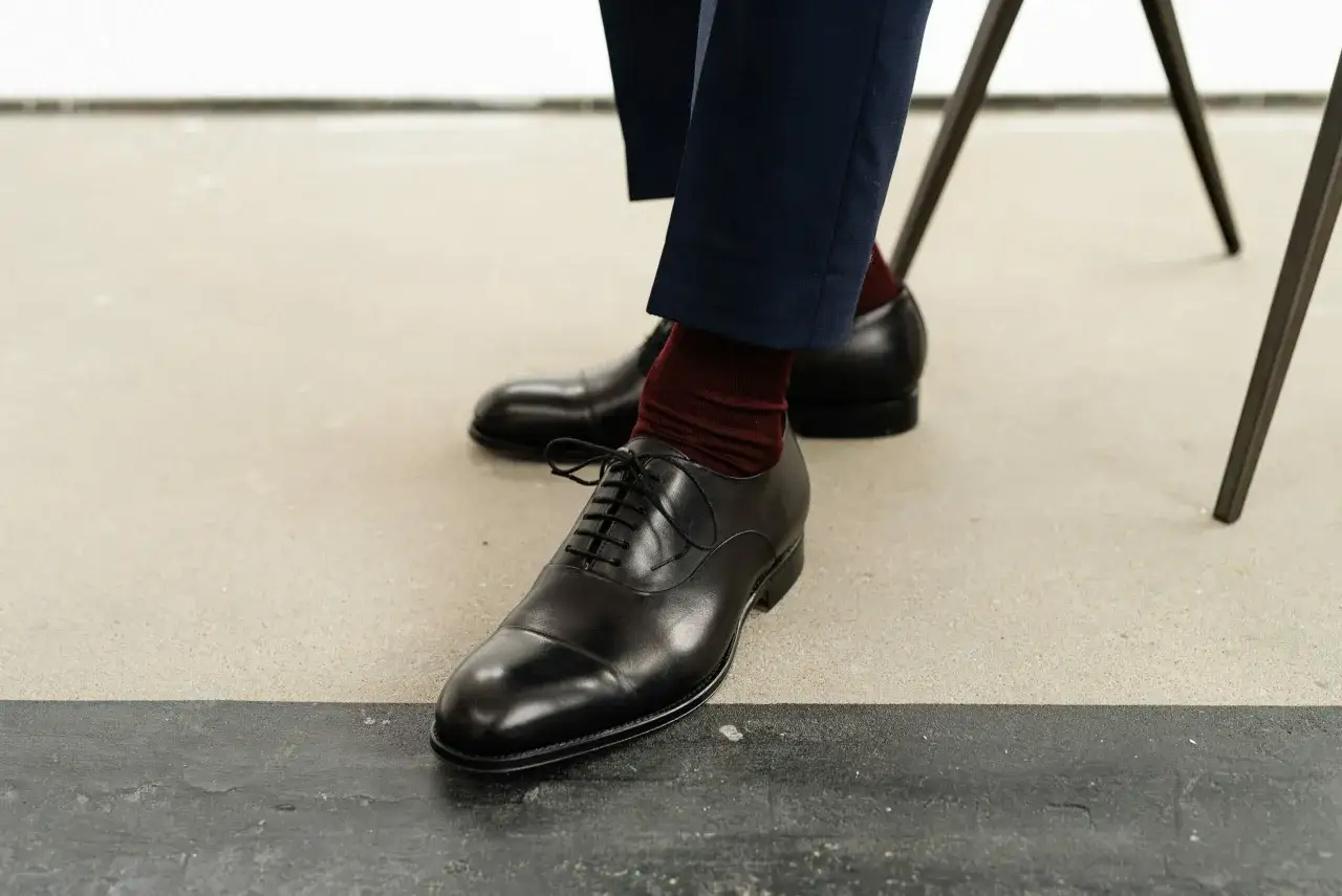 Eleganckie, czarne oksfordy z bordowymi skarpetkami. Idealne pytanie: jakie buty do smokingu? Te są świetnym wyborem.