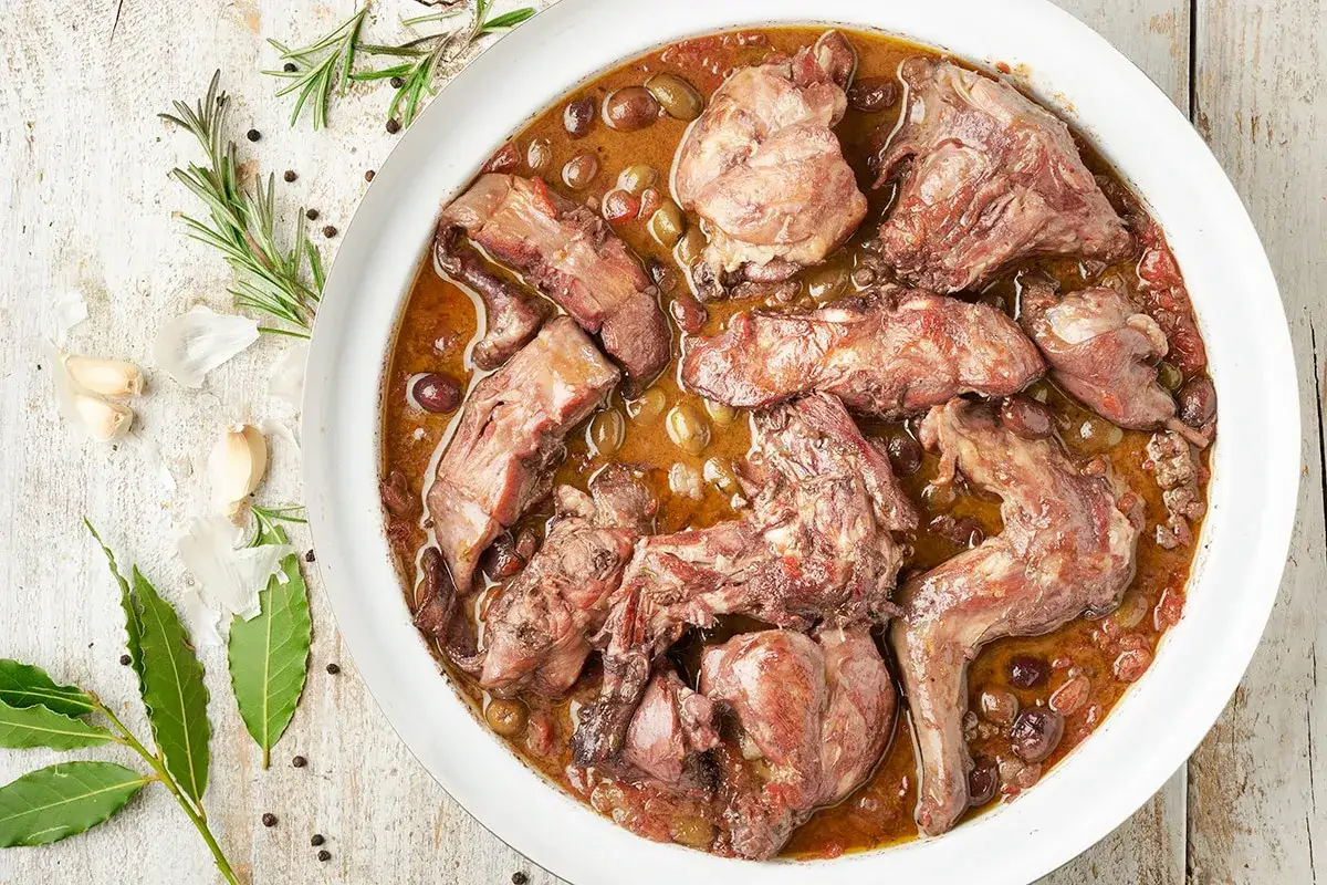 Un saporito coniglio in padella, cotto lentamente con olive e aromi, pronto per essere gustato.