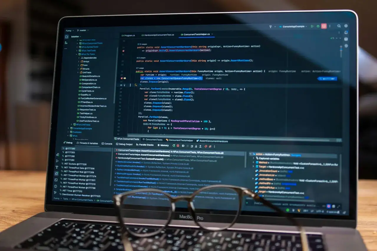 Laptop z otwartym edytorem kodu, wyświetlającym linie kodu w języku C#. Widoczne są nazwy plik&oacute;w i struktura projektu, co sugeruje pracę nad zaawansowanymi aplikacjami do programowania.